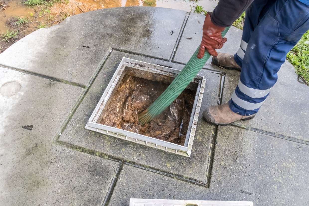 Septic Inspection in Kingston, NY — Technician pumping a septic tank through a square access opening