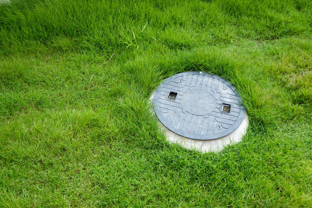 Septic access lid seated flush in a healthy green lawn in Hurley, NY