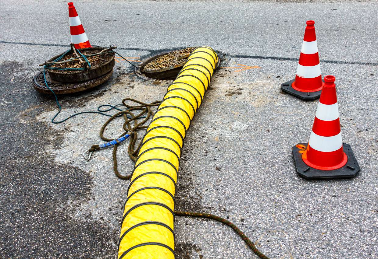 Sewer Snaking / Roto-Rooter Service in Kingston, NY — Drain hoses and safety cones set up at a work site