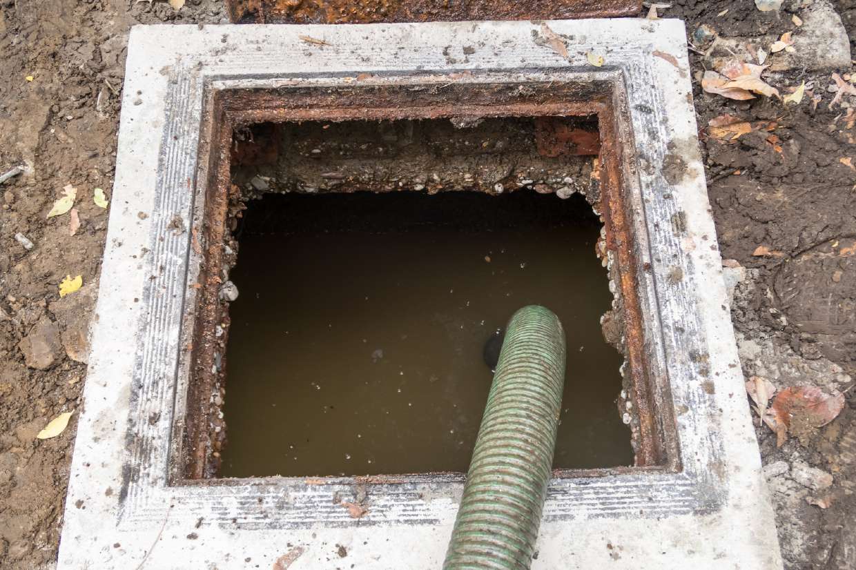 Suction hose pumping out a concrete septic tank