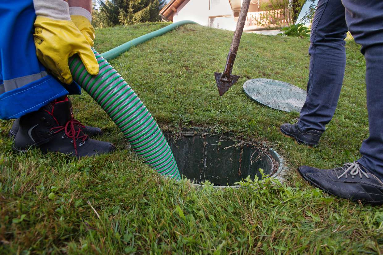 Pump hose lowered into a septic tank access lid in a back yard in Kingston, NY