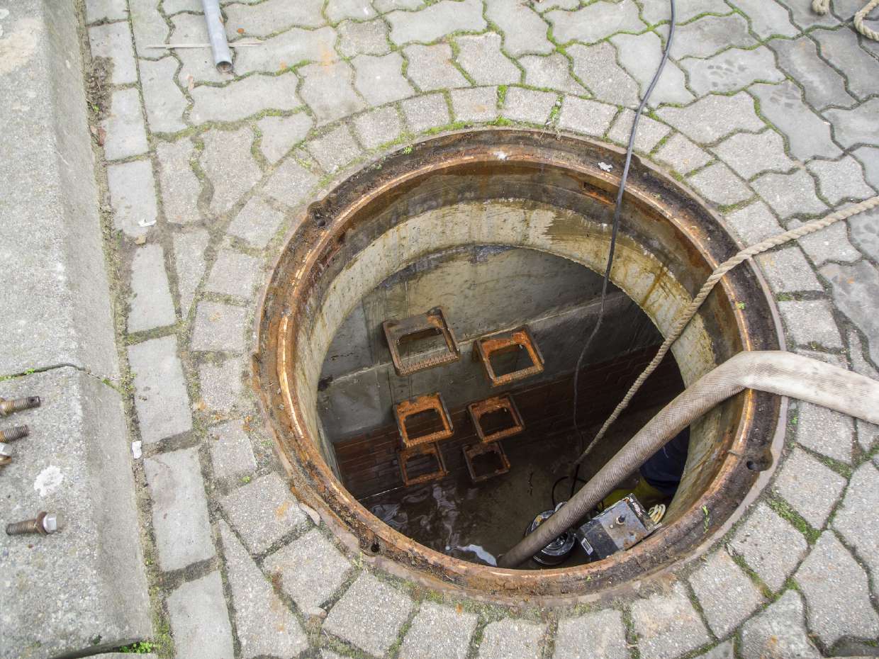 Sewer Snaking / Roto-Rooter Service in Kingston, NY — Open manhole in a paved driveway