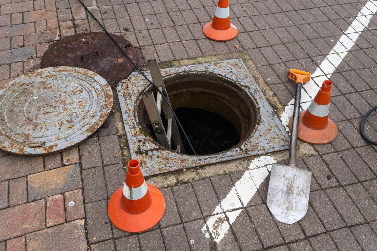 Septic Inspection project in Kingston, NY — Open manhole with safety cones on a brick drive