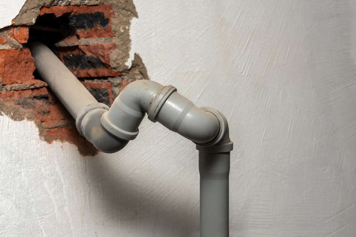 Exposed drain piping on the exterior of a home